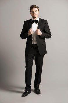 Man wearing tuxedo standing in front of grey background