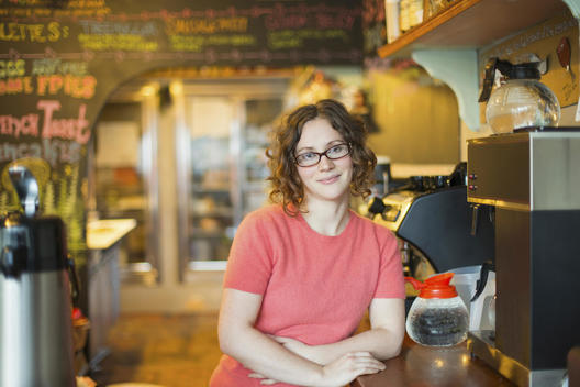 A coffee shop and cafe in High Falls called The Last Bite. A woman leaning on the counter, by the coffee machine.