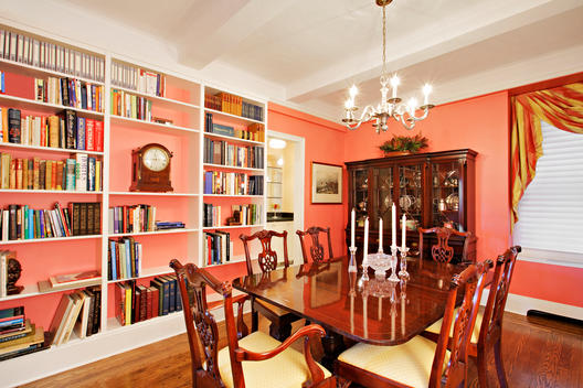 Brightly Lit Salmon Colored Dining Room With Bookshelves