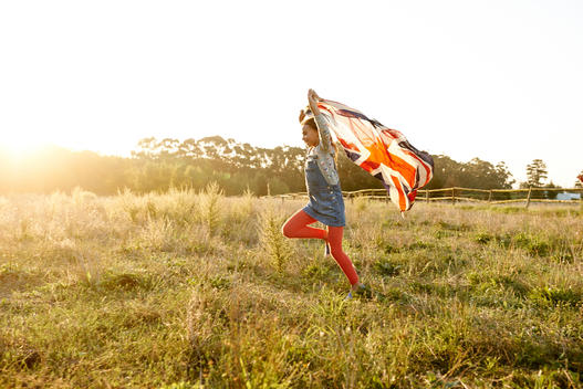 girl running with english flag on a grass field on sunset