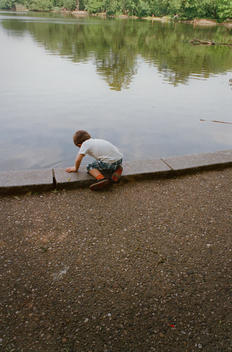 Young boy by the water\'s edge in Prospect Park, Brooklyn, New York