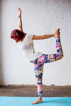 A young woman holding a dancer yoga pose