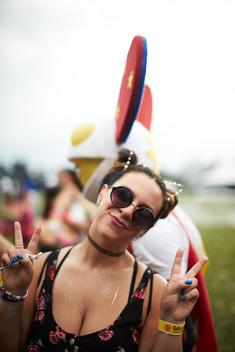 A woman in rave attire with peace signs up.