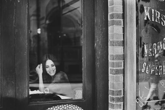 Black and White Image of Woman at Caf? Smiling out Window