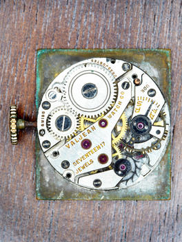 Antique Watch Back Showing Parts On Wood.