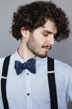 A profile portrait of a well dressed brunette man in a studio setting.