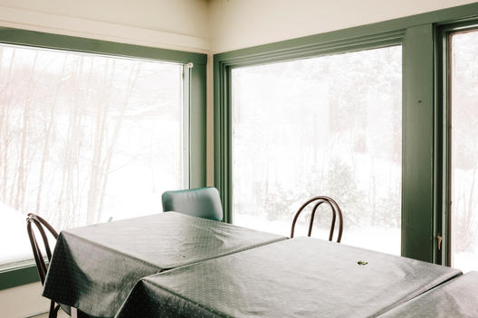 Tables and chairs in a corner of a ski lodge during winter.
