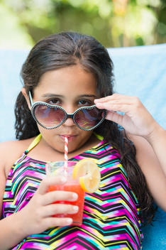 Mixed race girl sipping juice at poolside