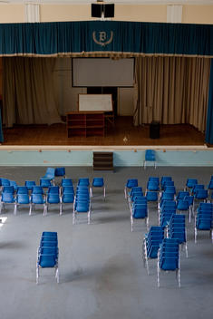 Stacks Of Blue Chairs In An Abandoned School Auditorium