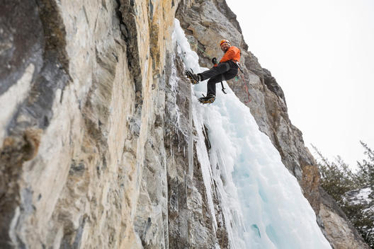 Low angle view of man descending ice wall in mountains