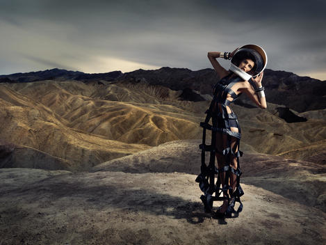 Portrait of a woman in her 20\'s in astronaut helmet and wearing a haute couture gown in Death Valley National Park, California.