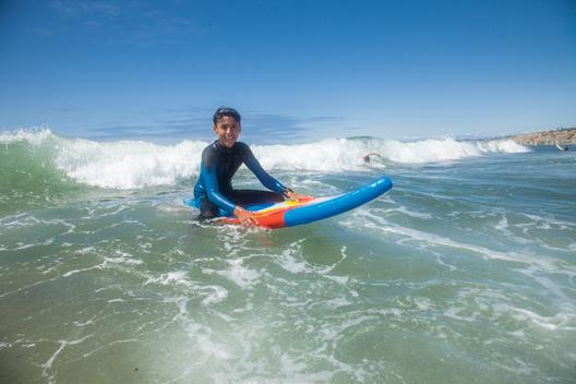 A young man floating on the water on his surfboard in the ocean while taking a break from surfing in the ocean on a sunny day in San Diego, California