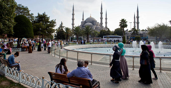 People gather around the parks, and especially place with many touristic attraction is Sultanahmet Square in this image Blue Mosque is appear while covered Turkish girls are walking by the pool.
