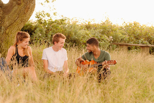 Friends playing guitar in tall grass