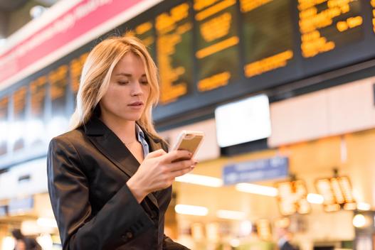 Young businesswoman in railway station reading smartphone texts