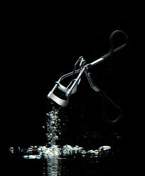 Eye Lash Curler And Water Bubbles Against Black