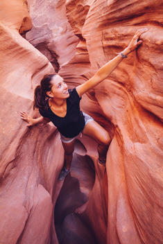 USA, Utah, Escalante, Peek-A-Boo and Spooky Slot Canyons, young woman climbing in gorge