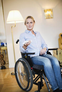 Disabled woman in wheelchair using remote control
