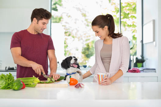Dog with couple cooking in kitchen