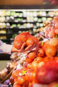 Close up of man holding bag of onions in grocery store