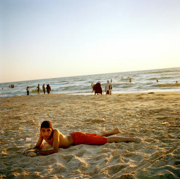 A young Palestinian boy lies on the sand wearing his swimming attire, on Gaza beach in Gaza City, Palestine.