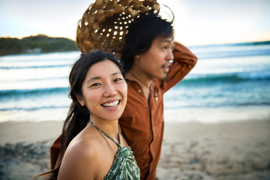 Young asian couple walking hand in hand on the beach at sunset