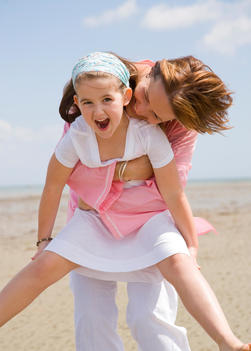 Mother lifting and embracing daughter laughing and screaming