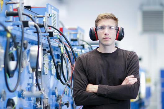 Portrait of mid adult male wearing ear protectors in engineering plant