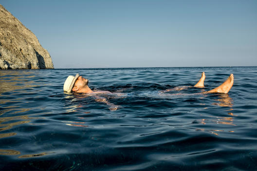 man floating in water wearing hat