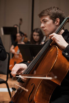 Caucasian man playing cello in orchestra