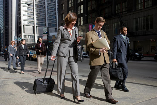Business Colleagues Talk And Walk Down A Busy Chicago Street.
