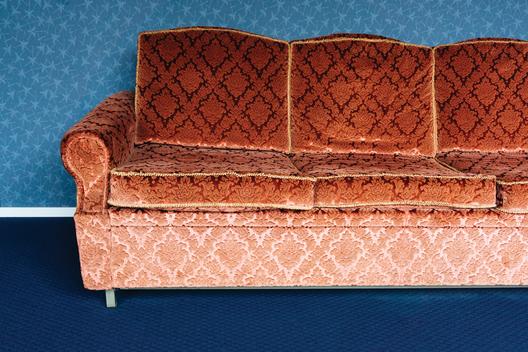 Still life of red couch with blue wallpaper backdrop