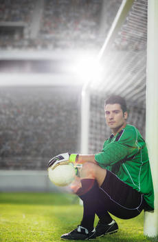 Goalie holding soccer ball by net