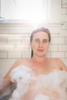 Woman in tub with bubbles.