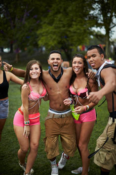 A group of concert goers in rave attire, making faces in a field.