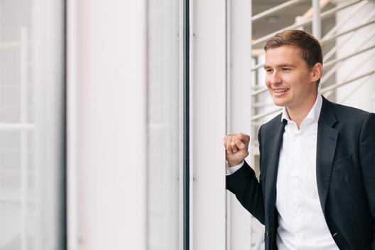 Portrait of young business consultant standing and looking outside the window