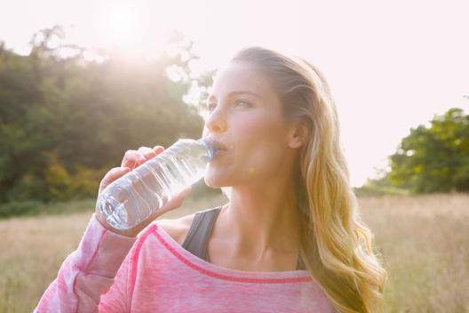 Woman in sportswear drinking from water bottle