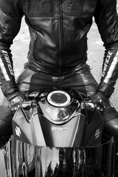A motorcycle rider with leather suit and gloves sitting on his motorcycle
