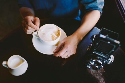 Woman\'s Hands with Coffee and Vintage Camera