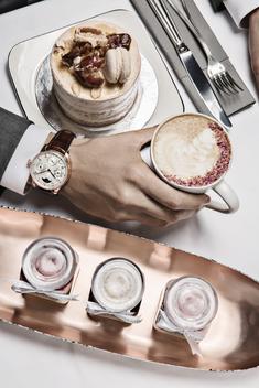 Close up details of hands with fine cakes plus luxury jewellery and watches.