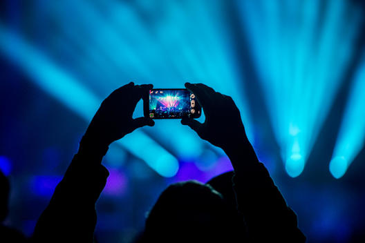 A person holding up an android phone taking pictures at a concert.