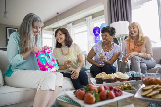 Woman opening birthday gift at party