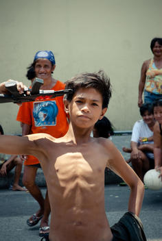 Shirtless Boy Playing With Fake Gun In Intramuros (Old Colonial Manila), People Laughing In The Background.