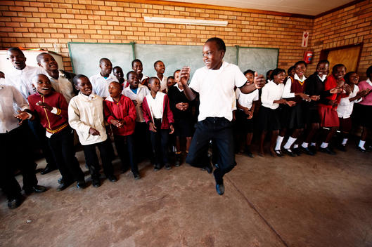 boy jumping while classroom sings