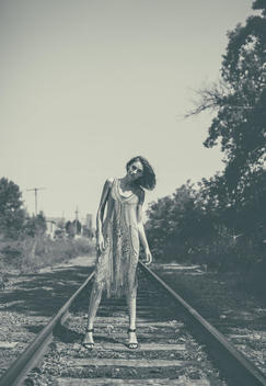 Monochrome photo of model standing on train tracks, flapper style dress on