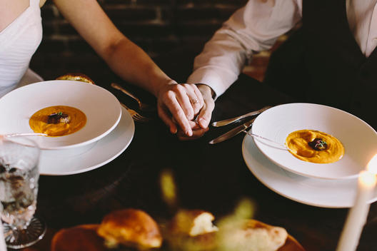 Couple Holding Hands at Table with Orange Soup