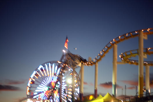 Roller coaster lit at night against dark blue sky.