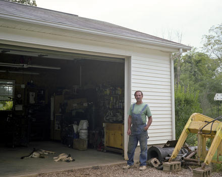 Portrait Of A Man Standing Outside His Work Shop With His Pet Dogs, Racine, Ohio, Usa.