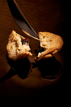 Mince pie broken into half with knife.
