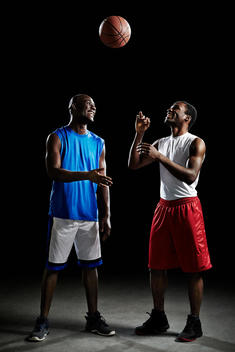 Studio shot of two basketball players with ball mid air